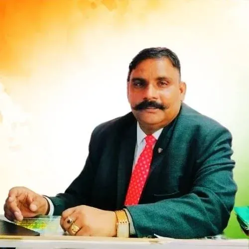 Managing Director of Dehradun Military Academy seated at his desk in formal attire.
